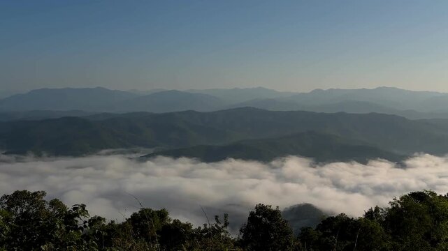 Cinematic slow pan over a vast sea of fog and rolling mountain ranges at Doi Samer Dao in Nan, Thailand.