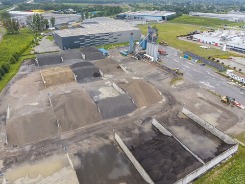 Skawina, Poland - 19 July 2026: Aerial view of the Colas bituminous mass plant featuring large piles of aggregate, storage silos, and industrial buildings in an urban setting.