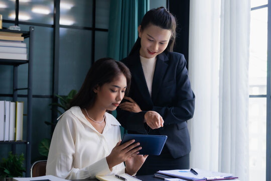 Asian boss businesswoman teaching intern working on tablet