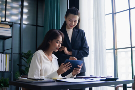 Asian boss businesswoman teaching intern working on tablet