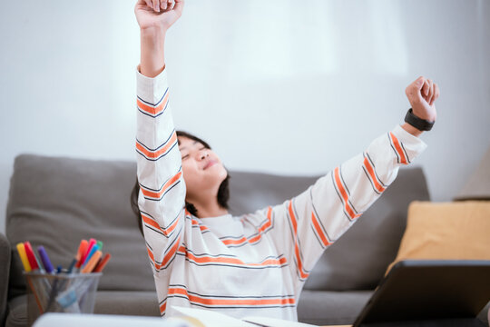 Young woman relaxing at home while studying on tablet during afternoon
