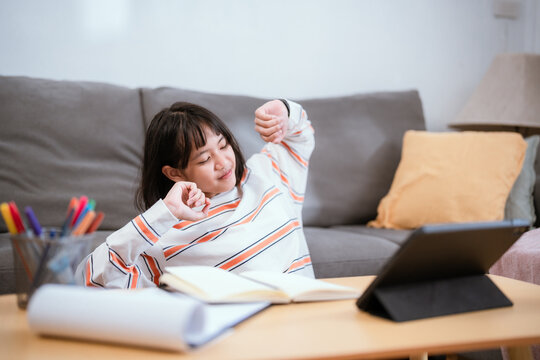 Young woman relaxing at home while studying on tablet during afternoon