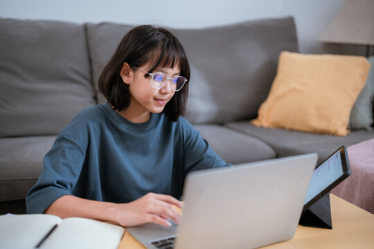 Young woman focuses on her laptop while working in a cozy living room during the day