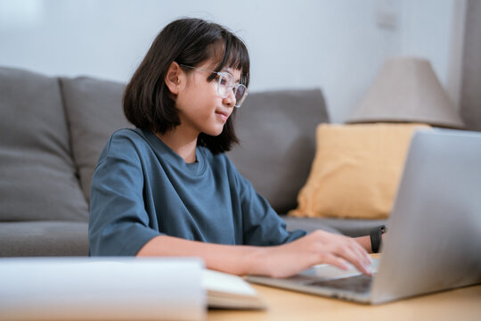 Young woman focuses on her laptop while working in a cozy living room during the day