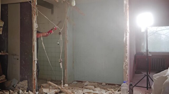 Static shot captures wall demolition as debris flies during renovation work
