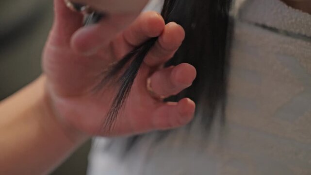 Close up of stylist shaping smooth dark hair with scissors in slow motion