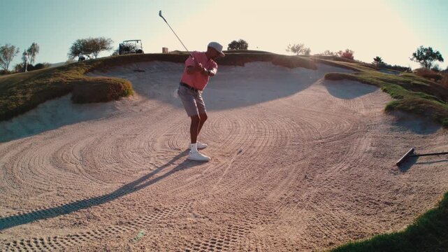 A golfer blasts out of a large desert bunker as sand explodes into the golden light, filmed in slow motion, great for short-game lessons and dramatic sport reels.