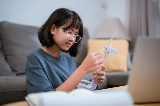 Young girl builds a model while sitting at a table in a cozy living room