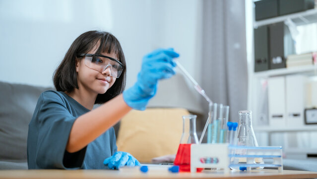 Young scientist conducting experiments at home with colorful liquids in glassware