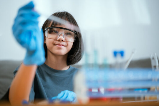 Young scientist conducting experiments at home with colorful liquids in glassware