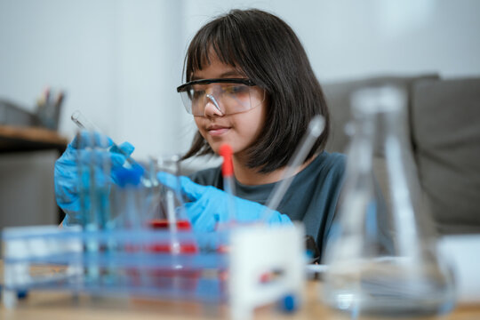 Young girl conducting a science experiment in a laboratory setting during the day