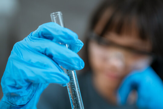 Young girl conducting a science experiment in a laboratory setting during the day