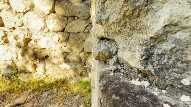 An ancient stone wall corner stands weathered in the bright sun. The rugged texture creates a sense of peaceful stability and historical wonder.