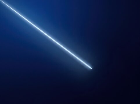 A bright streak of light moving across a dark blue night sky representing a falling star or a fast moving comet