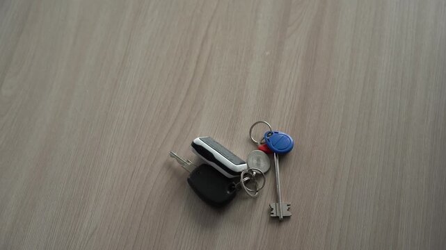 A scene of a calm morning: a cup of coffee and a ring of car keys lie on a light wooden table, symbolizing daily chores and the beginning of a new day. A tanned hand of an older man picks up the keys 