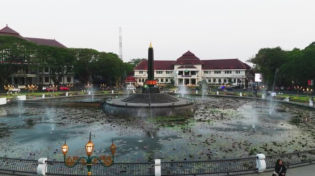 Malang, Indonesia - 27 July 2026: Aerial view of Tugu Monument and lotus pond surrounded by historic colonial architecture and lush greenery.