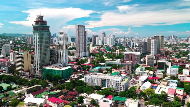 Cebu City, Central Visayas, Philippines - 13 July 2026: Aerial view of the modern skyline, dense urban buildings, and lush green trees under a bright blue sky.