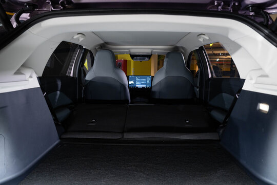 Interior view of modern SUV from rear cargo area, showcasing folded seats that create extended flat storage space. Dark upholstery and sleek design emphasize versatility