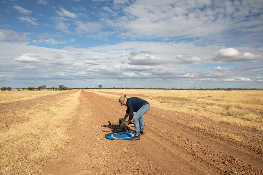 Man picking up agricultural drone from landing mat