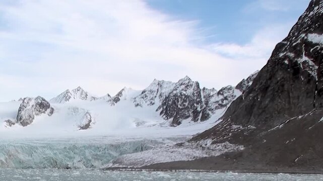 A sweeping vista captures a colossal glacier's shimmering expanse meeting icy waters in the Arctic.