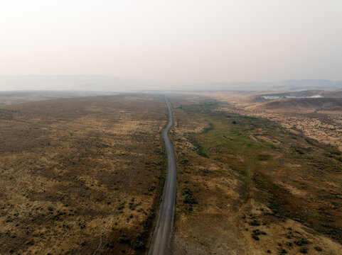 High-angle shot reveals a narrow road cutting through vast plains