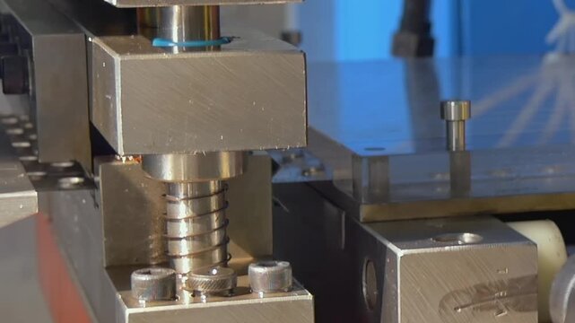Industrial steel components move through a heavy duty press in a quiet workshop.