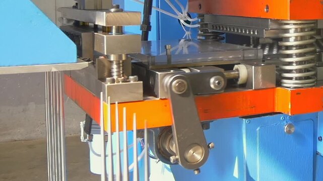 Mechanical arms rhythmically press silver rods in a clean workshop, showcasing the harmony of precision and automation through repetitive engineering mastery.
