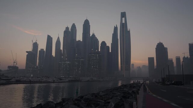 A wide establishing shot capturing the Dubai Marina skyline bathed in warm golden hour light during early morning. Soft, glowing sunlight.