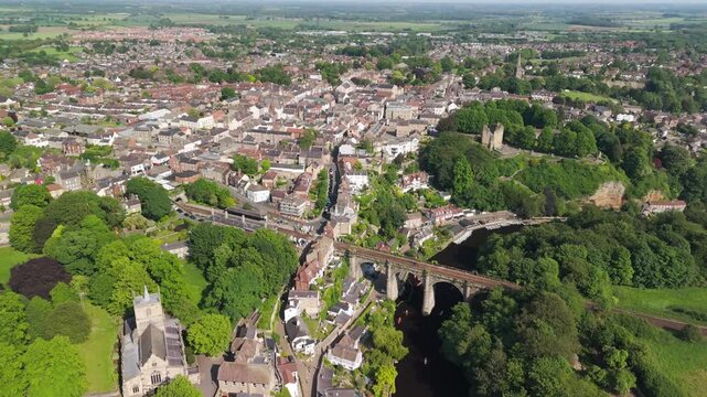 Birds-eye view of Knaresborough Viaduct spanning the River Nidd surrounded by lush green trees and traditional architecture.