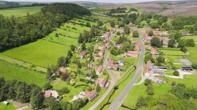 Aerial drone view flying over the picturesque village of Hutton-le-Hole in the North York Moors on a bright, sunny day