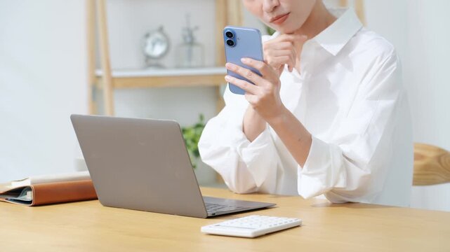 スマホとノートPCを見ながら悩むミドル女性。不安、心配、ニュース、アプリ、SNS、不満、疑問、DX