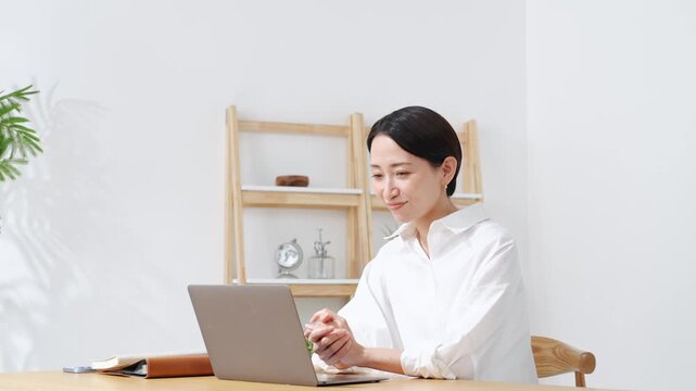 ノートPCに向かって話すミドル女性。web会議、ビデオ通話、レッスン、ウェビナー、配信、セミナー