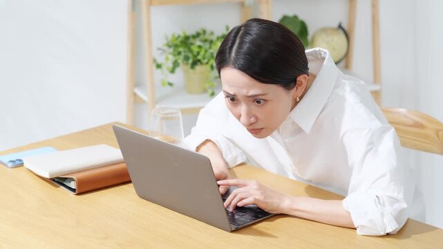 ノートPCにかじりついて見るミドル女性。真剣、仕事、投資、ギャンブル、熱中、集中、仕事、注目、不安
