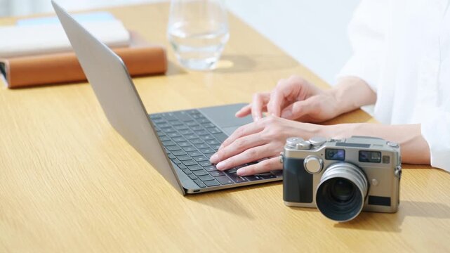 A woman using a camera and a laptop. Photography, editing, shooting, photographer, female photographer, image processing, auctions, listing items.