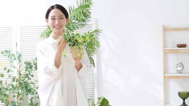 植物を持つミドル女性。ガーデニング、園芸、観葉植物、趣味、お手入れ、インドア、インテリア、笑顔、栽培