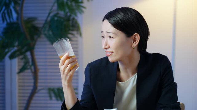 暗い部屋でお酒を飲む女性。ビール、ウイスキー、飲み会、居酒屋、バー、スナック、宅飲み