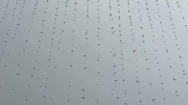 Water droplets falling in vertical lines against a gray sky
