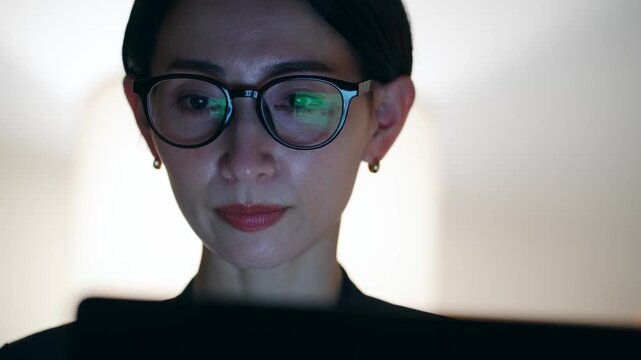 暗い部屋でパソコンを見るミドル女性。残業、夜、オフィス、仕事、作業、SE、エンジニア、画面、開発