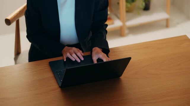 A middle-aged woman looking at a computer in a dark room. Desk work, remote work, freelance, work, systems engineer, engineer.
