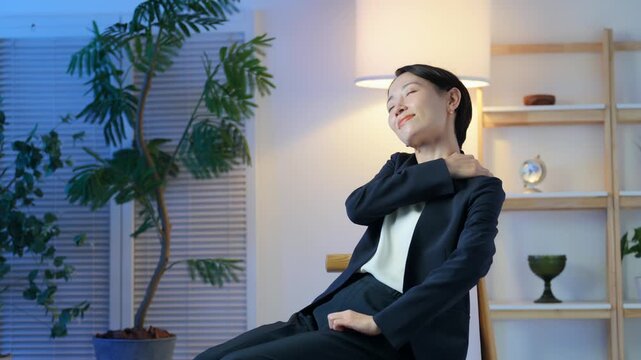 暗い部屋でリラックスする女性ビジネスパーソン。ストレス、疲れ、肩こり、休憩、残業、帰宅、夜、息抜き