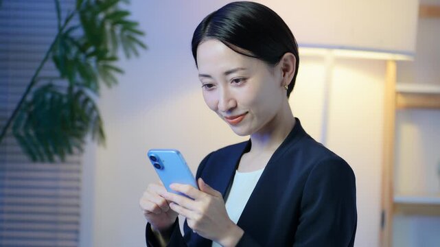 暗い部屋でスマホを見る女性。アプリ、SNS、メール、動画、DX、ビジネス、ゲーム、夜中、検索、通販