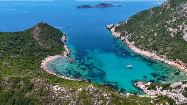 Kerkira, Corfu, Greece - 29 June 2026: Aerial view of Porto Timoni beach featuring turquoise waters, lush green hills, and boats anchored in the bay.