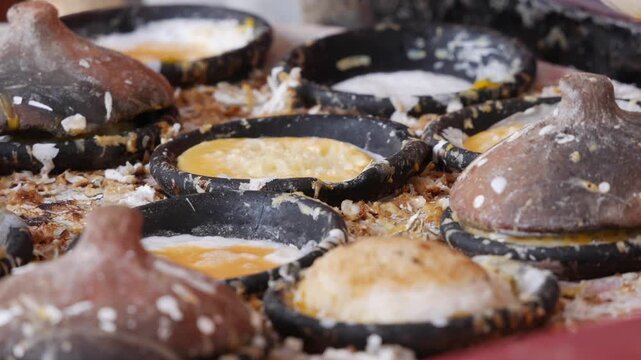 Small batter cakes bake and brown in round molds on a hot griddle at a market food stall. Local cuisine.