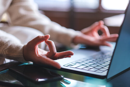 Closeup image of a woman hands in lotus pose over laptop computer for stress relief concept