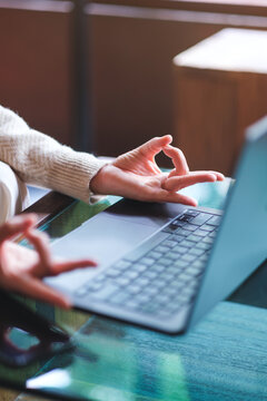 Vertical closeup image of a woman hands in lotus pose over laptop computer for stress relief concept