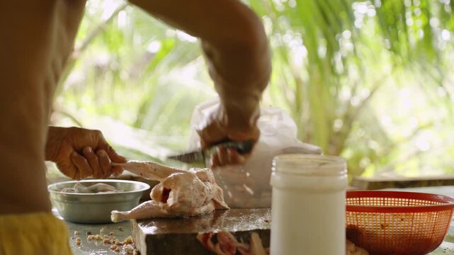 Person Slicing Raw Chicken and Placing It in a Plastic Bag