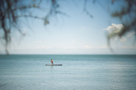 Stand-Up Paddleboarder on Lake Sevan with Snow-Capped Caucasus Mountains