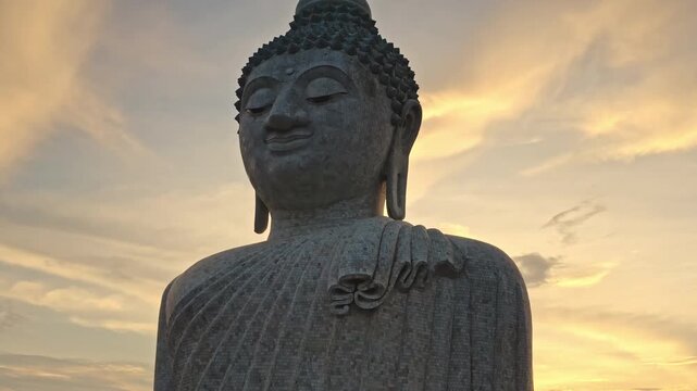 Close up shot of Big Buddha portrait statue appearing as a majestic landmark. Symbolizing spirituality, peace and meditation against a dramatic twilight sky. Phuket tourist attraction. Travel Thailand