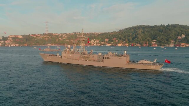 Istanbul, Istanbul, Turkiye - 30 June 2026: Aerial view of a Turkish Navy frigate sailing on the Bosphorus with a helicopter on its deck and coastal city in the background.