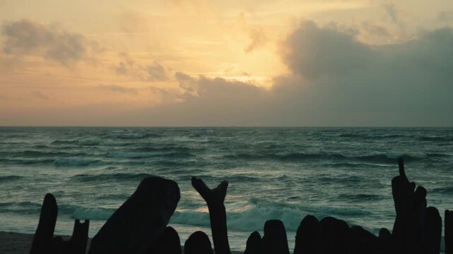 Silhouetted Hands Making Rock and Point Gestures Against a Golden Sunset Ocean